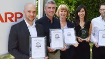 Sharp team holding framed certificates