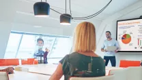 Office workers in a meeting room with presentation on screen