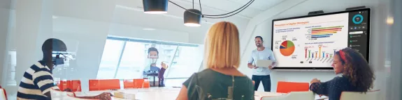 Office workers in a meeting room with presentation on screen